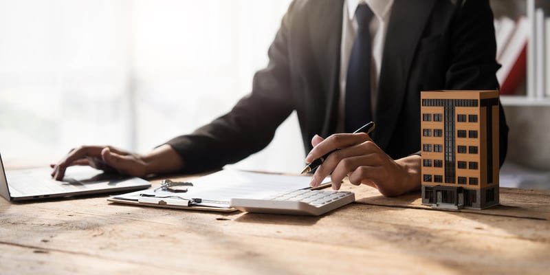 Entrepreneur working at a desk while calculating which is the best commercial business loan for him.