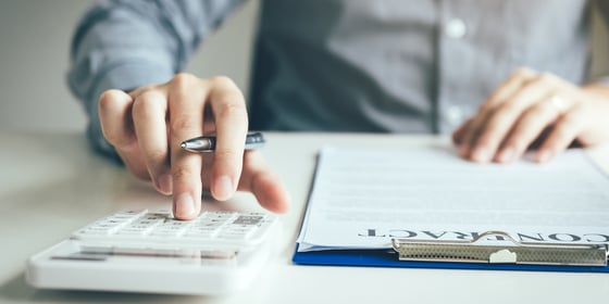 Commercial real estate investor using a calculator to determine if he should sign a commercial loan refinance contract