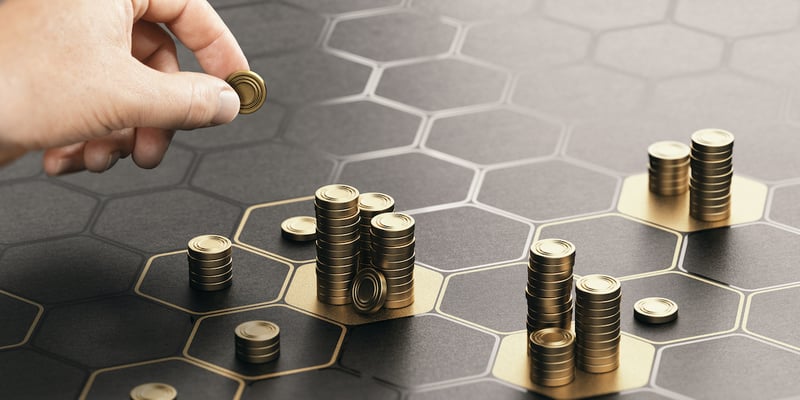 Person adding coins to a grid, representing portfolio diversification through hard money lender investing