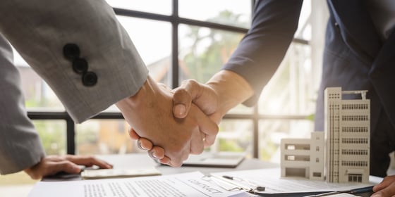 Business owner shaking hands with a lender because he knows how to get a business loan for commercial real estate.