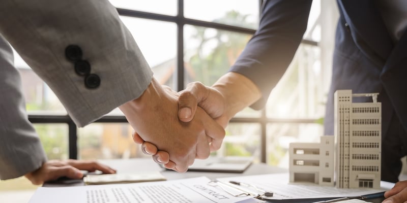 Business owner shaking hands with a lender because he knows how to get a business loan for commercial real estate.