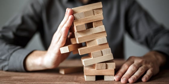 Investor holding a leaning tower of blocks, symbolizing how to manage investment risk.