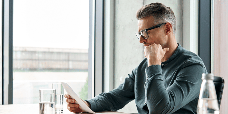 Male investor staring at a report, considering the pros and cons of private equity investments