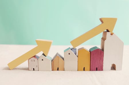 Colorful wooden homes gradually increasing in size with arrows pointing upward